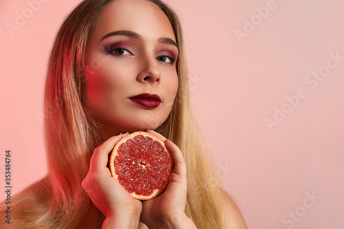 Beautiful girl with grapefruit closeup, isolated in studio background. Beauty fashion shooting, space for text, food nutrition concept