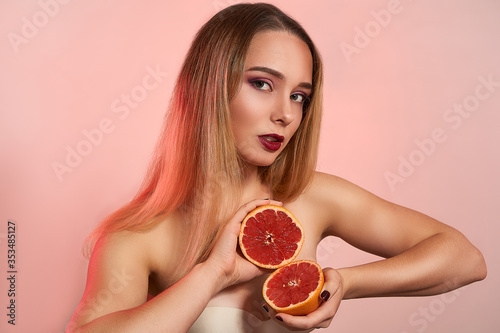 Beautiful girl with grapefruit, isolated in studio background. Beauty fashion shooting, space for text, food nutrition concept
