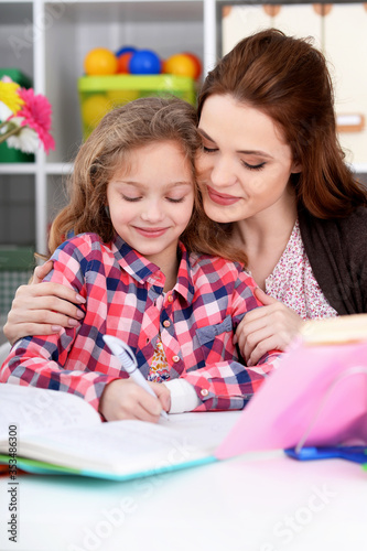Beautiful little cute girl with mother doing homework