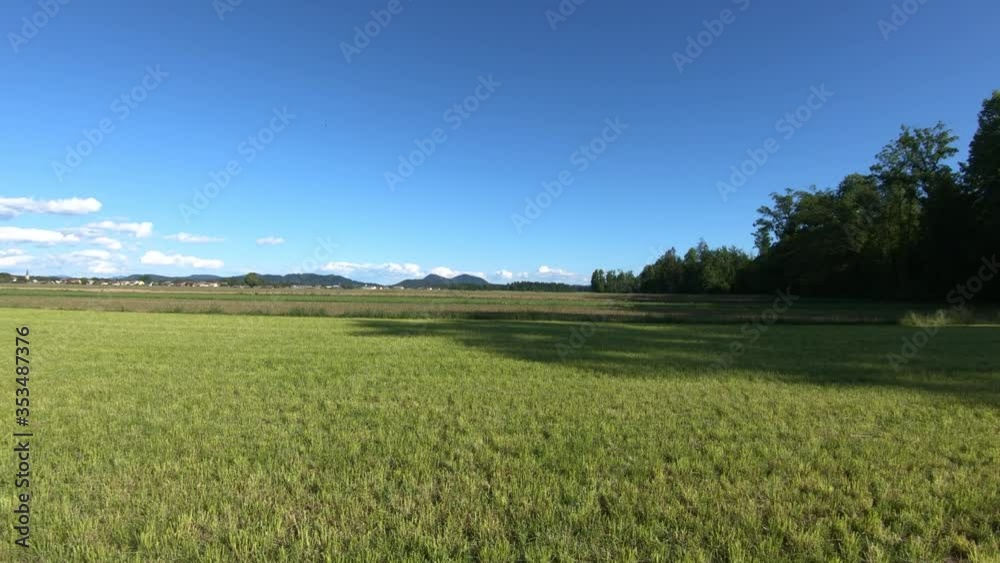Freshly harvested cut agriculture field in countryside on a soft bright warm day. Mountains in distance. Greenery theme. Wide shot, forward dolly moving Freshly harvested cut agriculture field in countryside on a soft bright warm day. Mountains in distance. Greenery theme. Wide shot, forward dolly moving