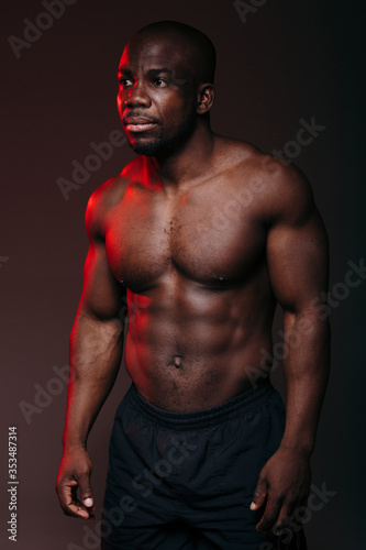 Portrait of a handsome muscular dark-skinned Pilates trainer showing muscles of the naked torso