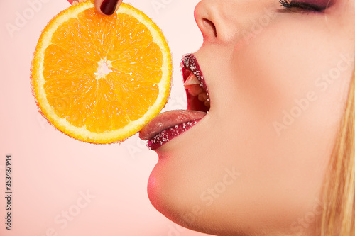 Closeup mouth, tongue and lips of girl in sugar with orange. Food, fashion concept