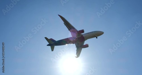Airplane flying over head in sunny blue sky