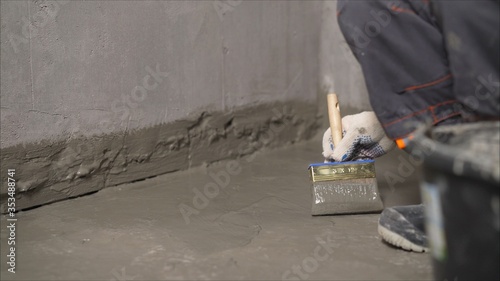 Waterproofing mortar on a concrete floor. A worker applies waterproofing to a concrete floor with a brush. Concrete floor repair. photo