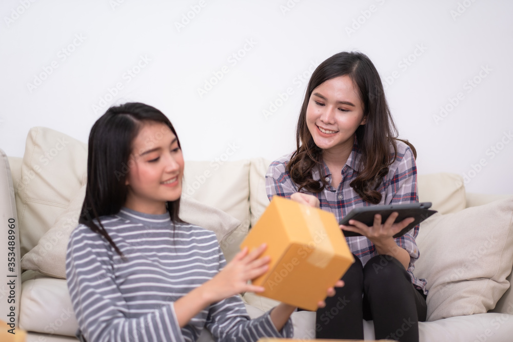 Two Asian female packing product and using tablet to checking order from customer shopping online and e-commerce at small office. Two Asian female packing product and using tablet to checking order from customer shopping online and e-commerce at small office.