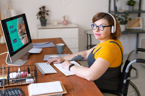 Photography Portrait of content young portly woman in wireless headphones sitting in wheelch