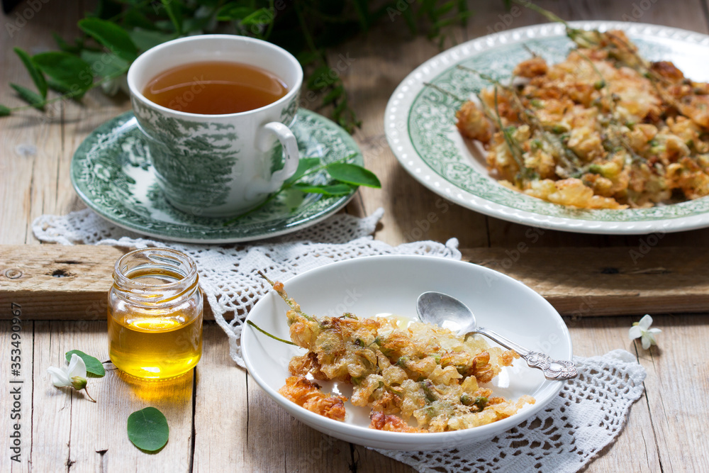 Robinia fritters served with tea and honey on a wooden table. Rustic style. Robinia fritters served with tea and honey on a wooden table. Rustic style.