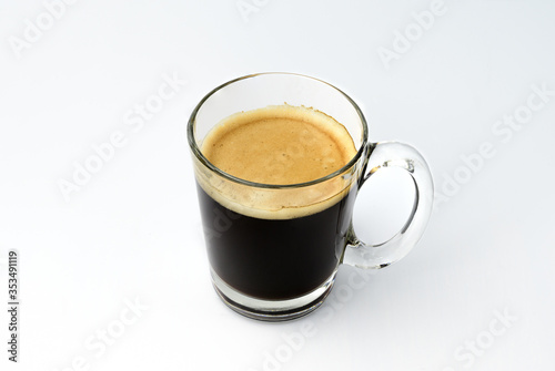 Black coffee, intense roasted coffee, Robusta, Froth caused by coffee machine. In clear glass with a single side handle. Hot drinks beverage that is bitter good for health. Isolated white background.