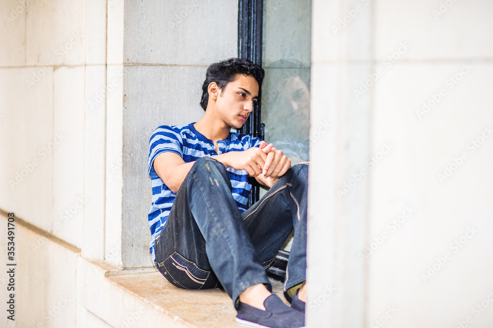 Lonely Asian American teenager thinking outside in New York City, wearing blue lines striped T shirt, broken fashionable jeans, cloth shoes, sitting on fame of window, looking inside, sad, depressed..