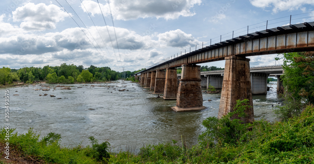 Fototapeta premium A railroad bridge made from stone and metal crossing the Broad River in Columbia, South Carolina taken from the Columbia Canal and Riverfront Park trail.