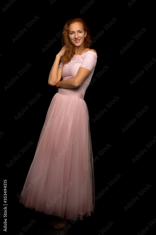 Red-haired young woman in the studio on a black background.