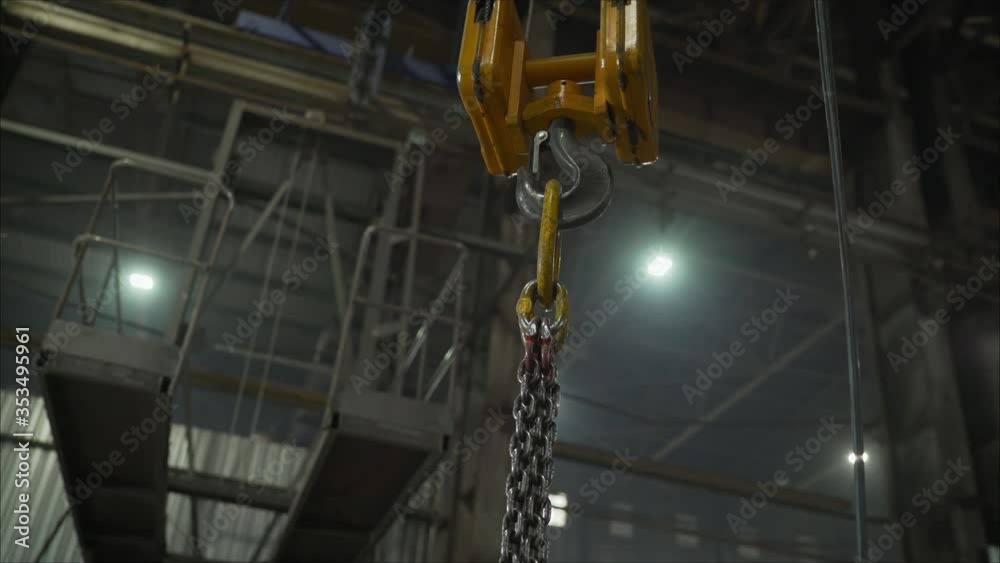 Low angle view of manual worker operating crane lifting sheet metal in industry. Crane in the factory lifts metal sheets Low angle view of manual worker operating crane lifting sheet metal in industry. Crane in the factory lifts metal sheets