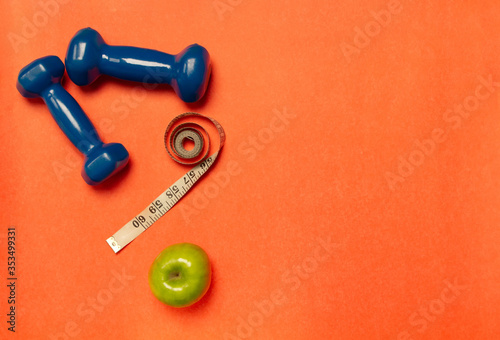 Dumbbells with a measuring tape and an apple on a bright background. Methods of dealing with excess weight.