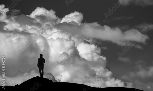 silhueta de homem olhando para montanha de nuvens