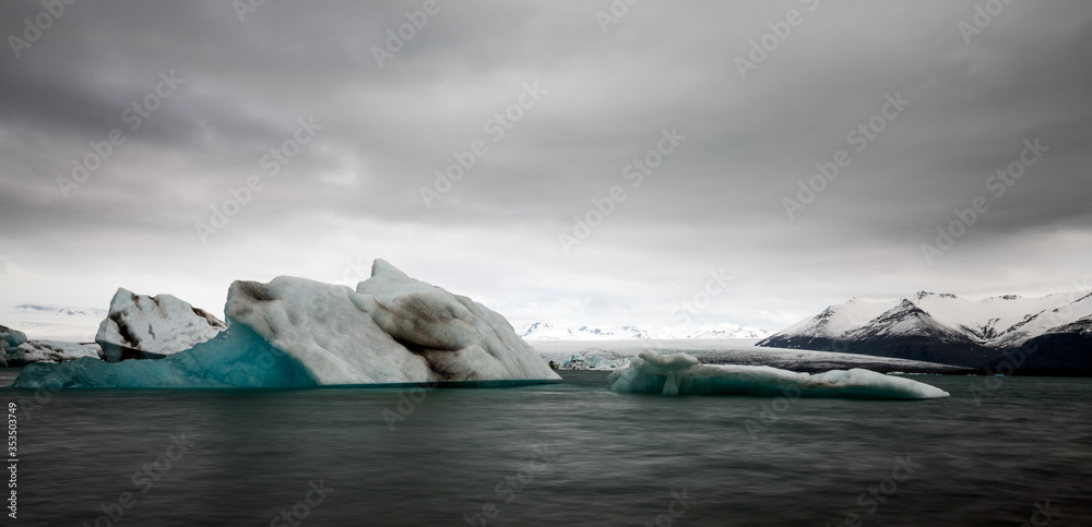 Long exposure panorama shot of melting crystal clear blue icebergs in Jokulsarlon glacier lagoon in Iceland.