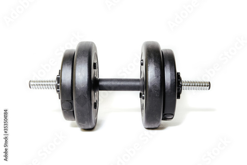 Dumbbells on a light background. The concept of sport and training, the weights lie on the ground. Black dumbbells ready for exercise, taking care of your figure and physical health.