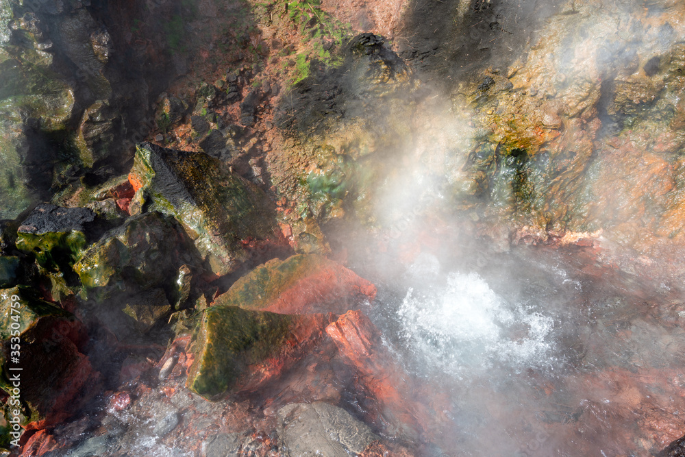 Boiling soil in geothermal area with hot steam and red volcanic textured rocks. Boiling soil in geothermal area with hot steam and red volcanic textured rocks.