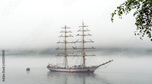 Big and tall sail ship in Geiranger fjord in Norway during misty day.