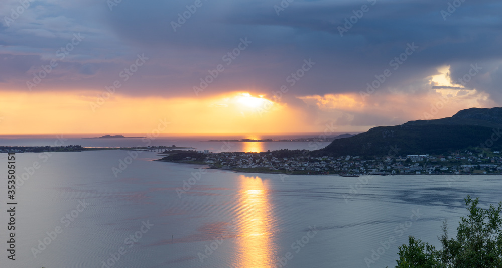 Sunset with rain clouds and colorful scenery over fjords and islands in Aalesund Norway.