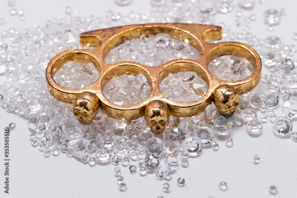 Brass knuckles and diamonds on a white background, top view