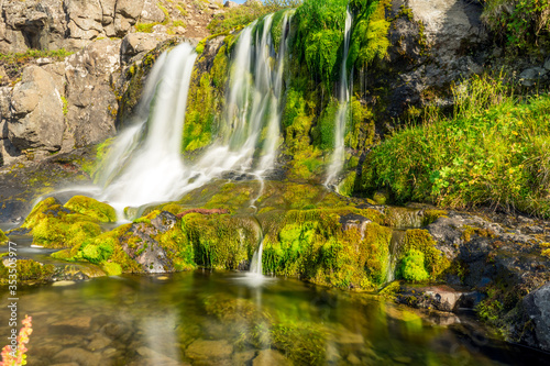 Fototapeta Naklejka Na Ścianę i Meble -  Green and colorful waterfall scenery with textured moss, clear and fresh water, cacades and landscape details.