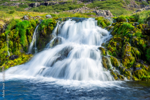 Green and colorful waterfall scenery with textured moss, clear and fresh water, cacades and landscape details.
