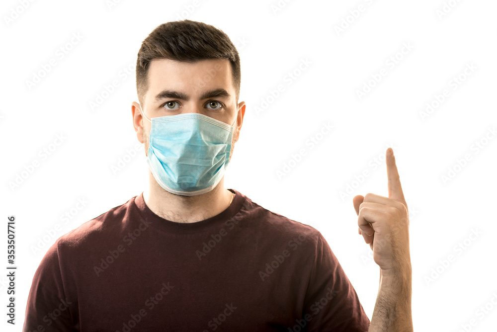 Young man in a mask from a virus, showing thumbs up, place for a mockup. Horizontal frame Young man in a mask from a virus, showing thumbs up, place for a mockup. Horizontal frame