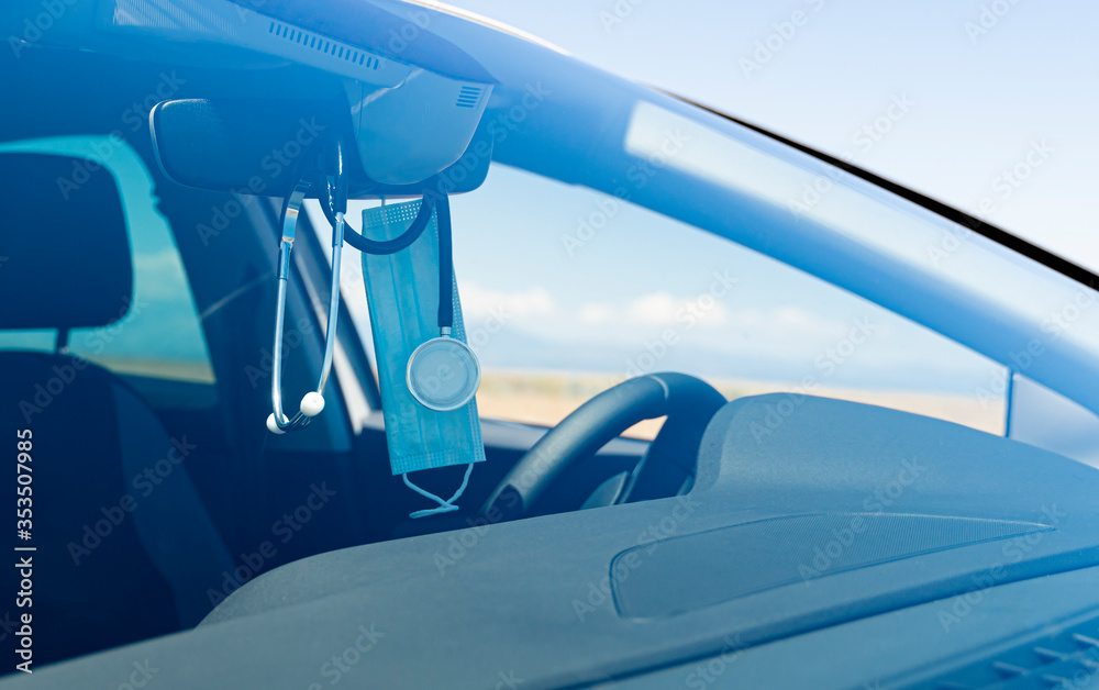 Blue surgical mask and a stethoscope hanging from the rearview mirror of a  medical car with the background slightly out of focus. Stock Photo | Adobe  Stock