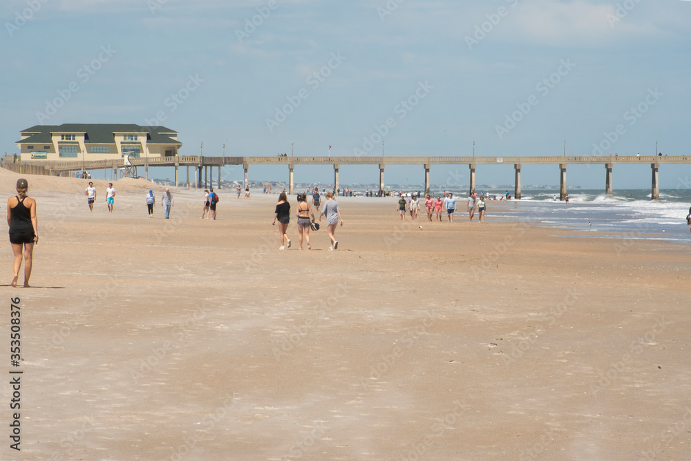 A young woman walks along a sparsely populated beach amid COVID-19. Social distancing was advised as the beach was open for exercise only.