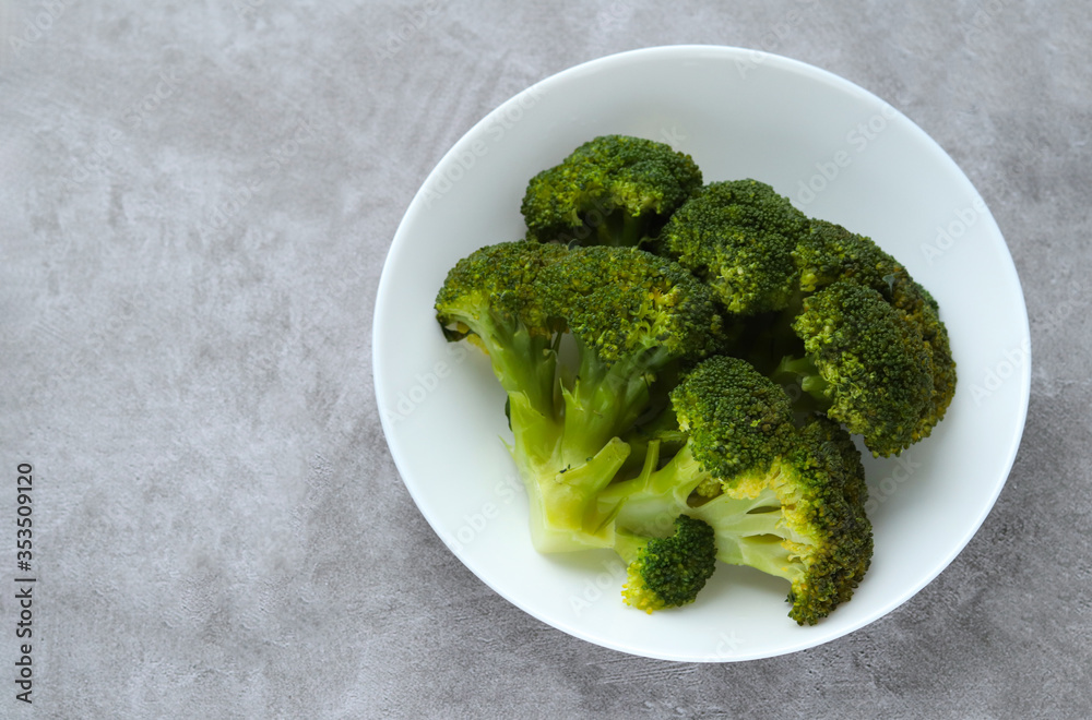 White plate with green fresh broccoli on a gray background. Proper healthy nutrition. Selective focus. Space for text. Copy space White plate with green fresh broccoli on a gray background. Proper healthy nutrition. Selective focus. Space for text. Copy space