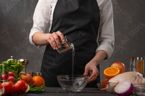 The chef pours water into a container on the background of vegetables and fruits. Preparing food, freezing in motion. Recipe book, gastronomy.