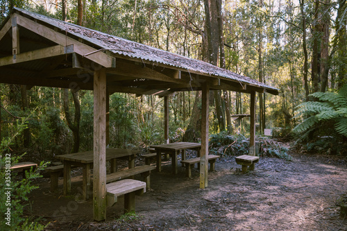 An old wooden rest stop in the forest with tables and benches. 