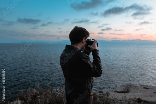 Young and curly photographer taking landscape picture of Calamosca hill at sunset photo