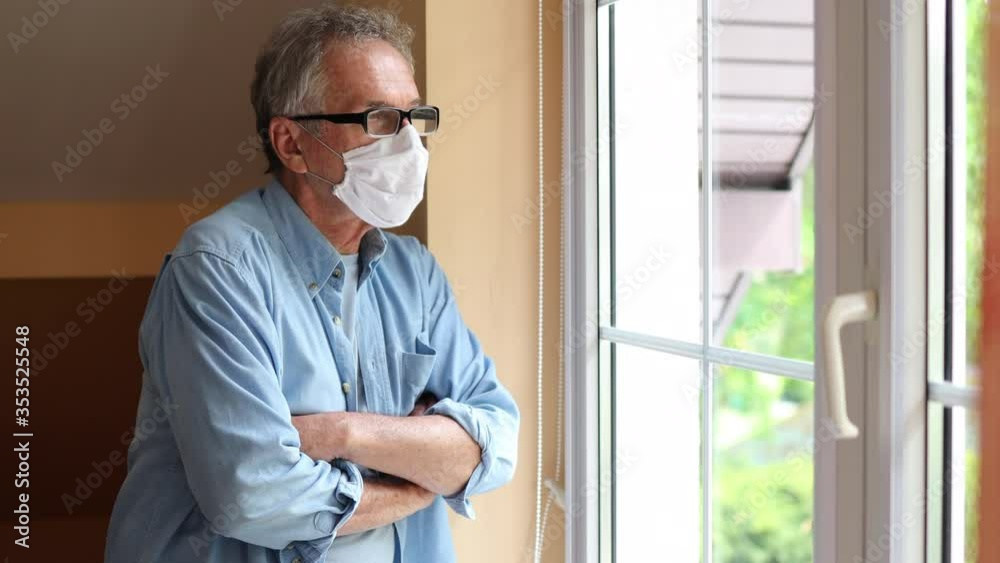 Senior man with face mask looking out of window
Senior man with face mask looking out of window