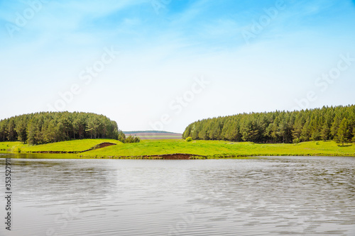 A small picturesque lake in calm weather, the banks are covered with forest.