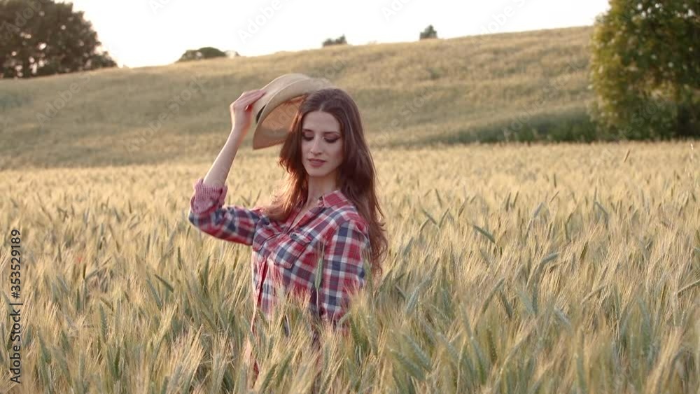 A young woman is touching the grass in a wheat field A young woman is touching the grass in a wheat field