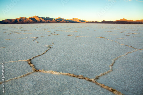 Uyuni Salt Flat Hexagonal Shaped Tiles Spreading Far Away at the Horizon at Sunrise with Volcanos and Mountains in Background photo