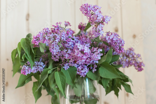 Lilac flowers in transparent glass vase. Charming bouquet of blooming lilac in the kitchen