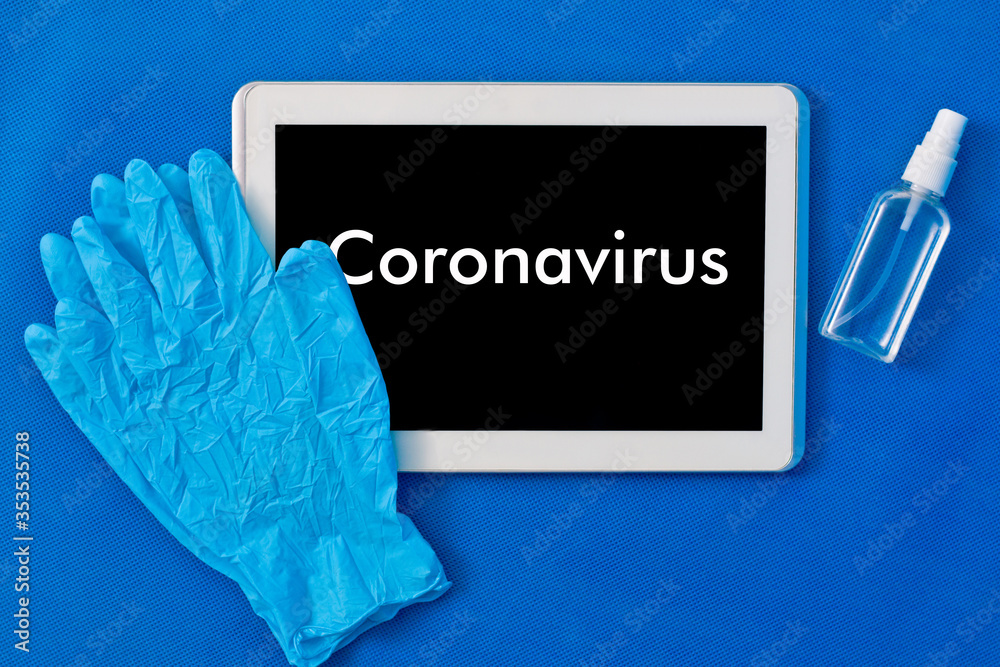Tablet PC and hygiene products disinfectant and rubber gloves with the inscription coronavirus, the concept of coronavirus