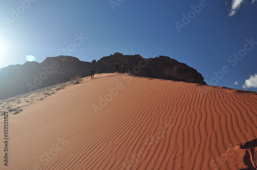 Children descending from a high  sandy dune in the Wadi Ram desert in Jordan. Great fun when traveling to a distant country.