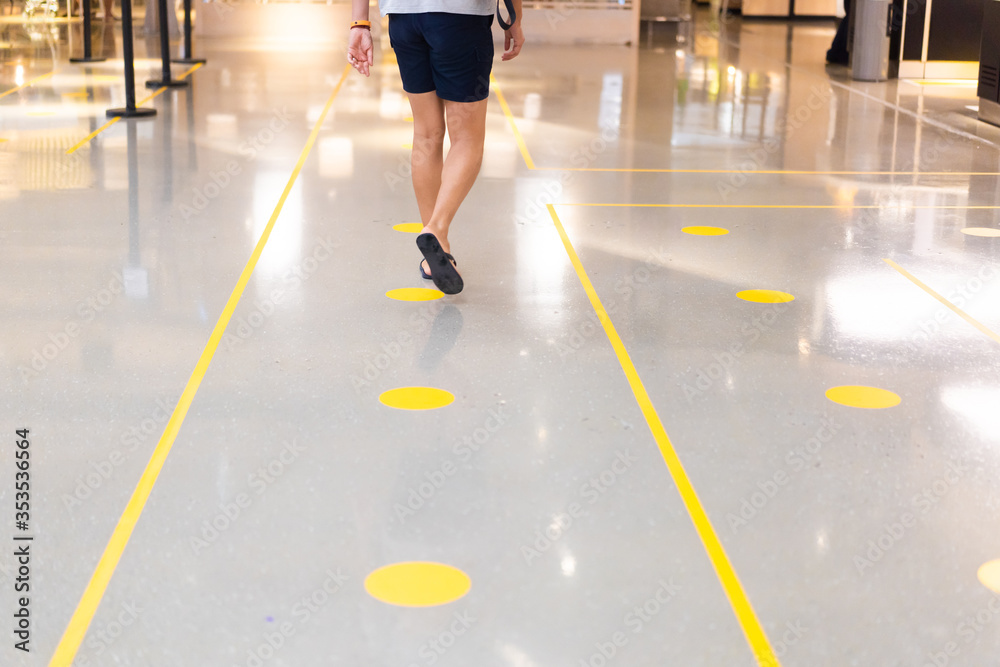 Man walking yellow dot in the mall.Please Keep Distance.Social Distancing between 2m.Man in walking line in department store.New normal Reopen, School, Office.Social distance, People.