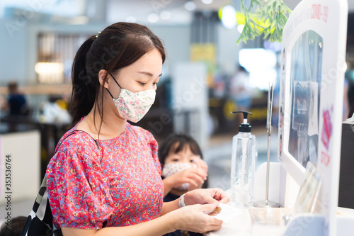 Woman wearing mask and paying money in cashier cafe restaurant in mall with partition shield.Reopen department store business.New normal new you.Mother and kid girl in grocery store.Social distancing.