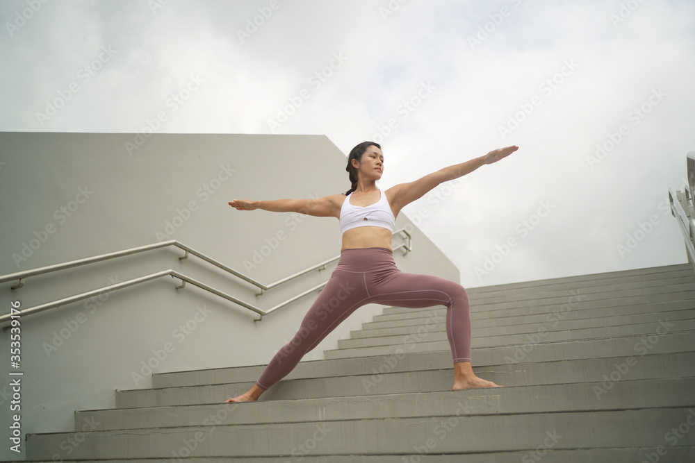 Obraz premium Street Yoga - Asian Chinese Woman doing yoga in public spaces