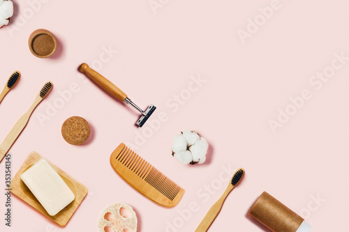 Zero waste accessories on pink background. Bathroom accessories on pink background. Natural bamboo toothbrush, sponges, cotton flowers, shaving brush. Flat lay, top view.
