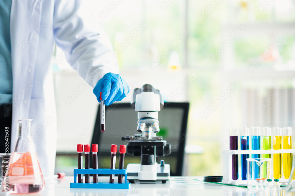 Professional Asian scientist or researcher man in work coat uniform select and holding colorful coronavirus or covid-19 vaccine sample in science lab Professional Asian scientist or researcher man in work coat uniform select and holding colorful coronavirus or covid-19 vaccine sample in science lab