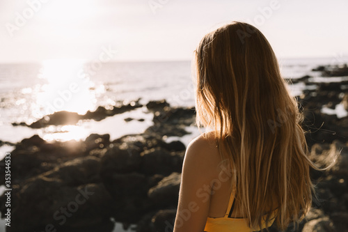girl in swimwear enjoying and walking on beach, in summer time, on the sunset. Portrait of happy young woman smiling at sea.