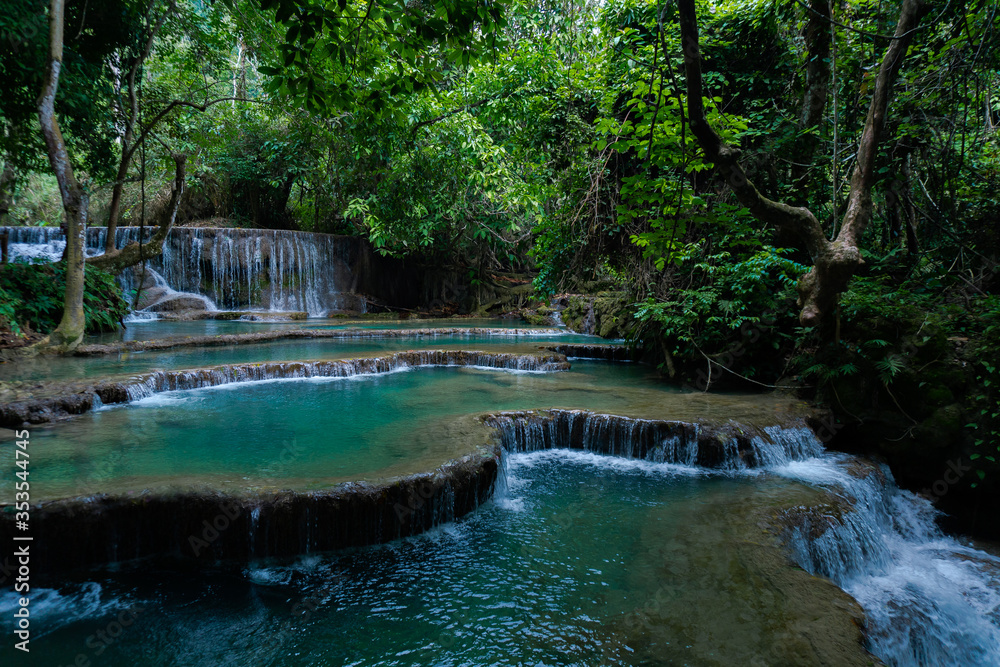 Naklejka premium Kuangsi Waterfall, lower level. The water cascades over the embankments creating beautiful pools that are used for swimming by locals and tourists in Luang Prabang, Laos.