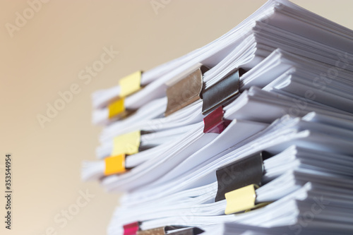 Fotografie Pile of student homework that assigned to student to be completed outside class on teacher desk separated by colored paper clips