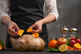 Chef cooks chicken for baking in the oven, decorates with fruits. Holidays, Christmas, New Year or a day of blessing. Menu, restaurant business, recipe book