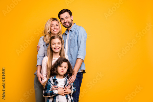 Photo wife mother lady handsome husband dad couple hug adopted little school girl daughter small son boy happy together wear casual shirts clothes isolated yellow color background